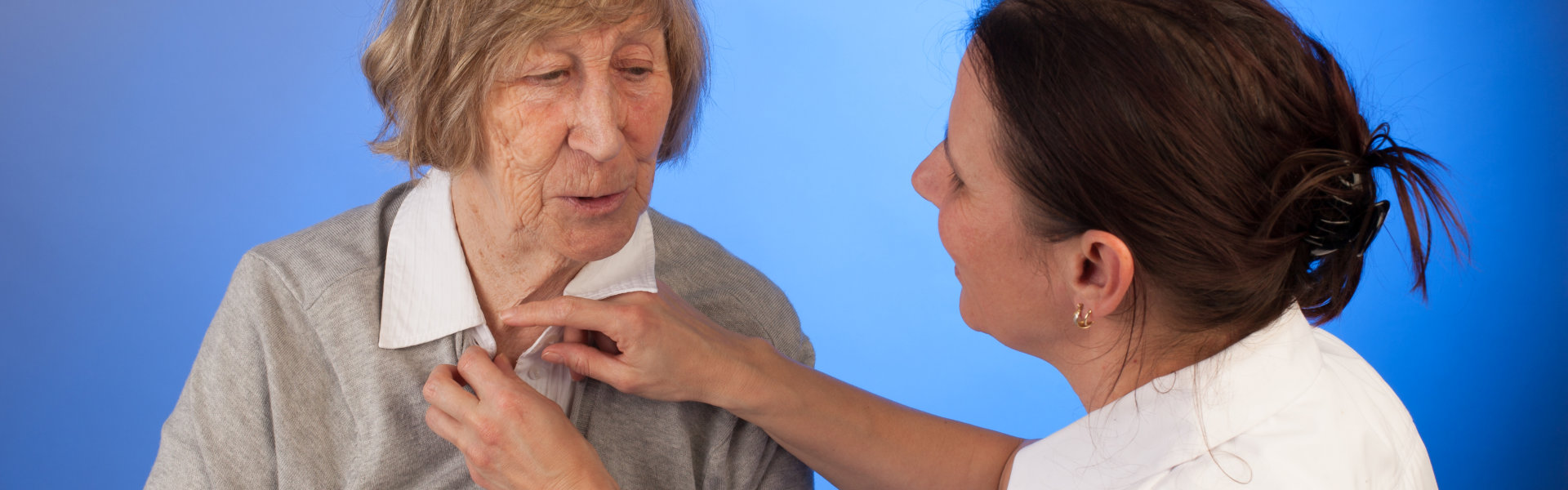 Nurse helps a senior women with dressing